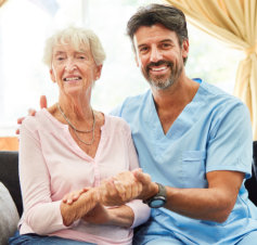 elderly woman and male caretaker smiling